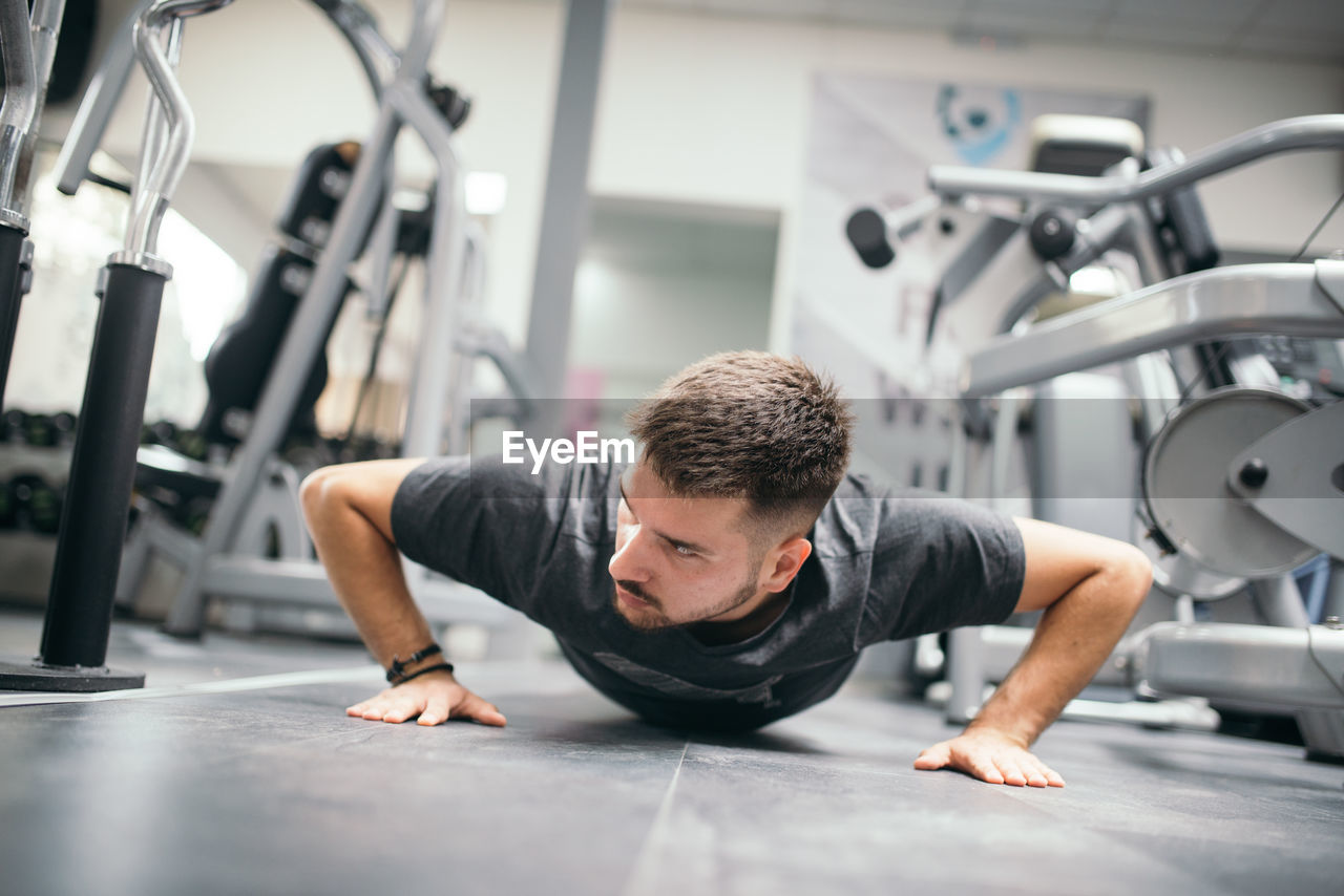 Muscular attractive guy doing push-ups in gym