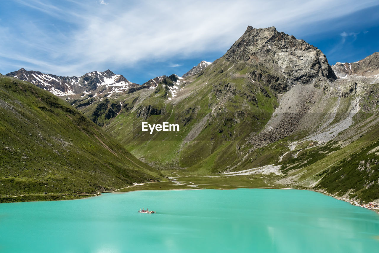 Scenic view of lake by mountains against sky