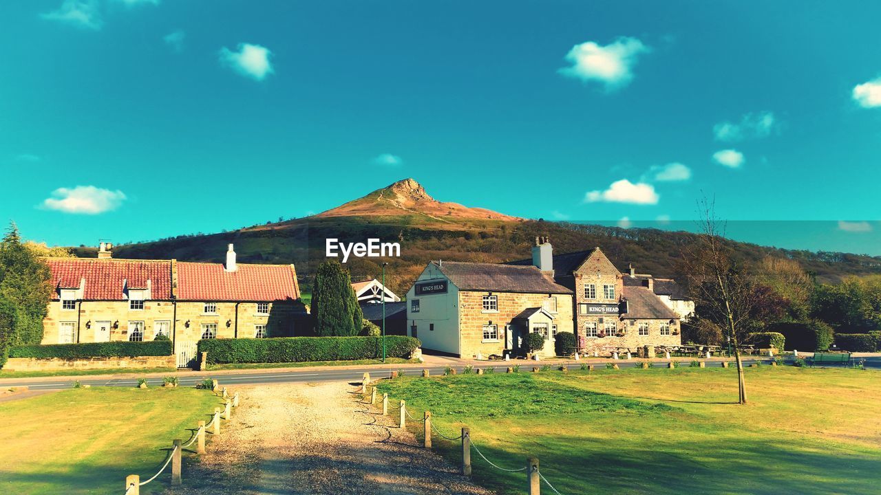 HOUSES ON FIELD AGAINST SKY