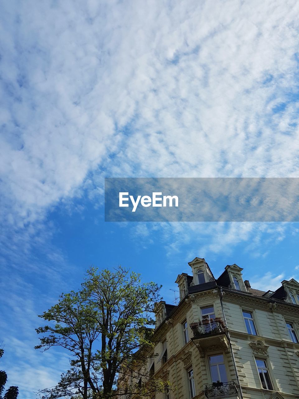 LOW ANGLE VIEW OF BUILDING AGAINST CLOUDS