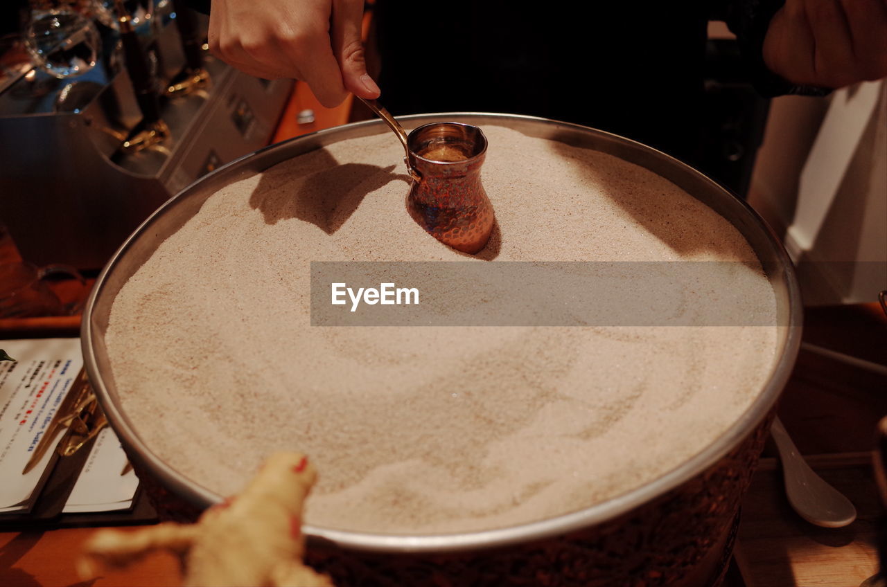 Cropped hand of person holding container over food