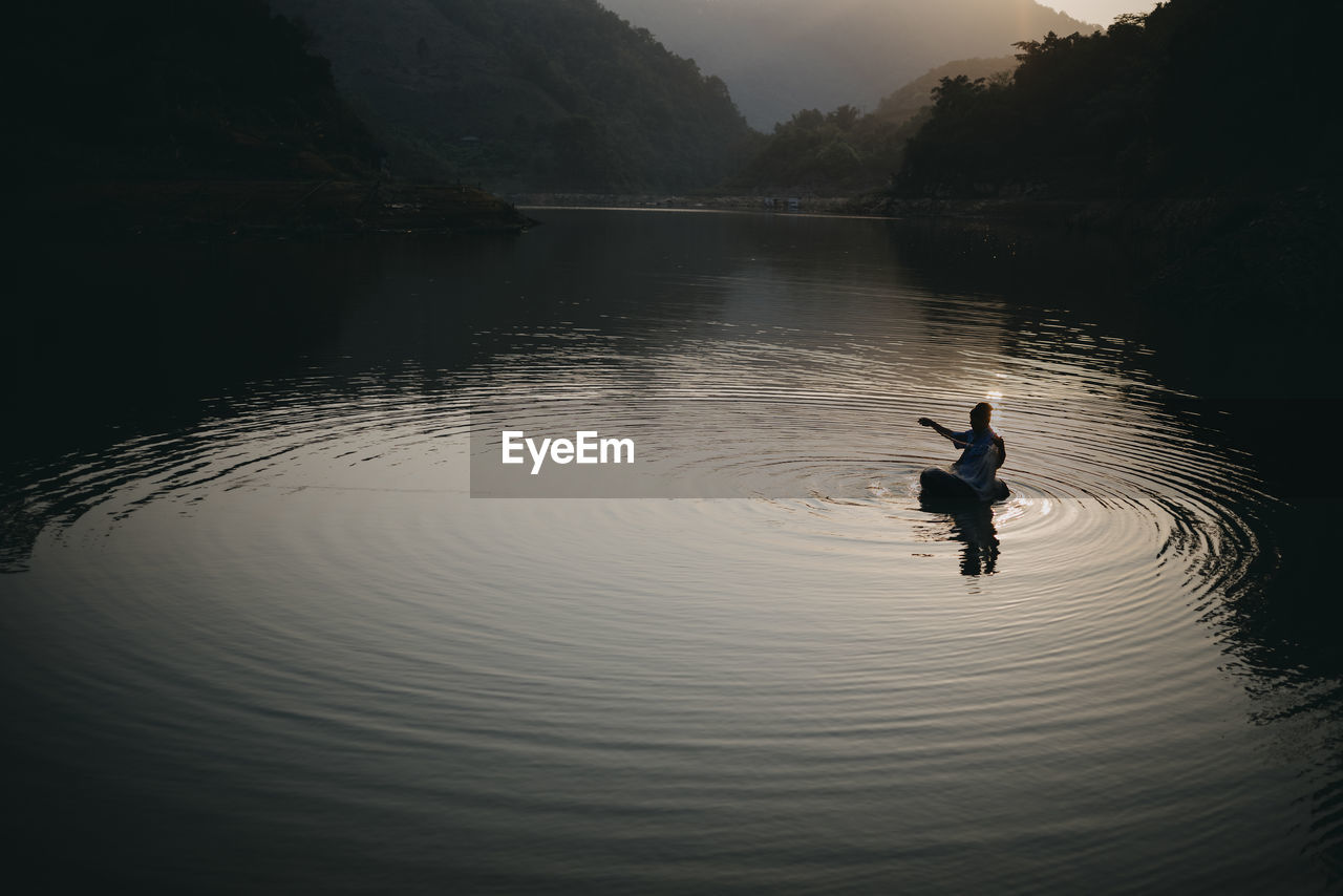 High angle view of silhouette man in lake