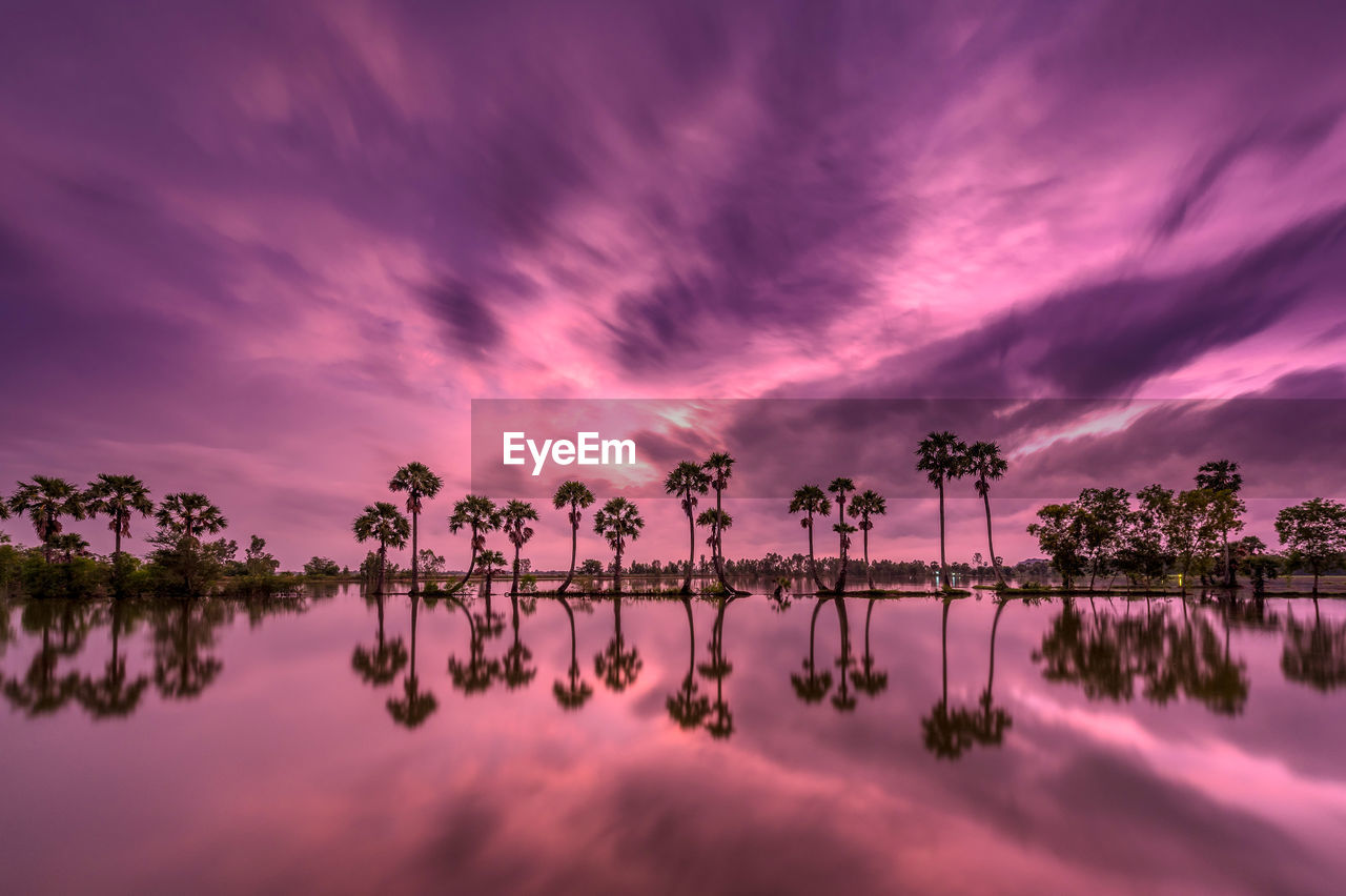 Scenic view of lake against dramatic sky during sunset