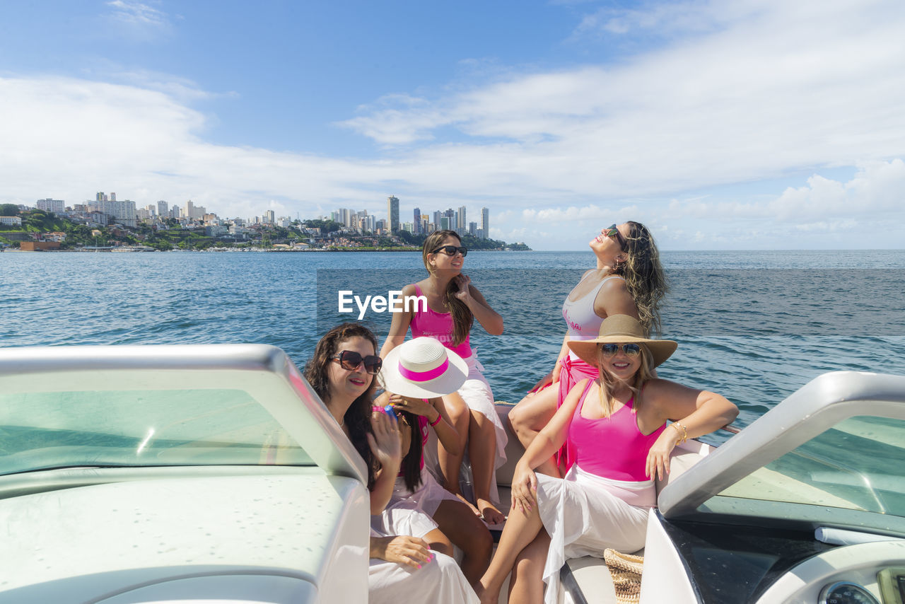 Women in bikini sitting on a boat wearing pink outfit. 