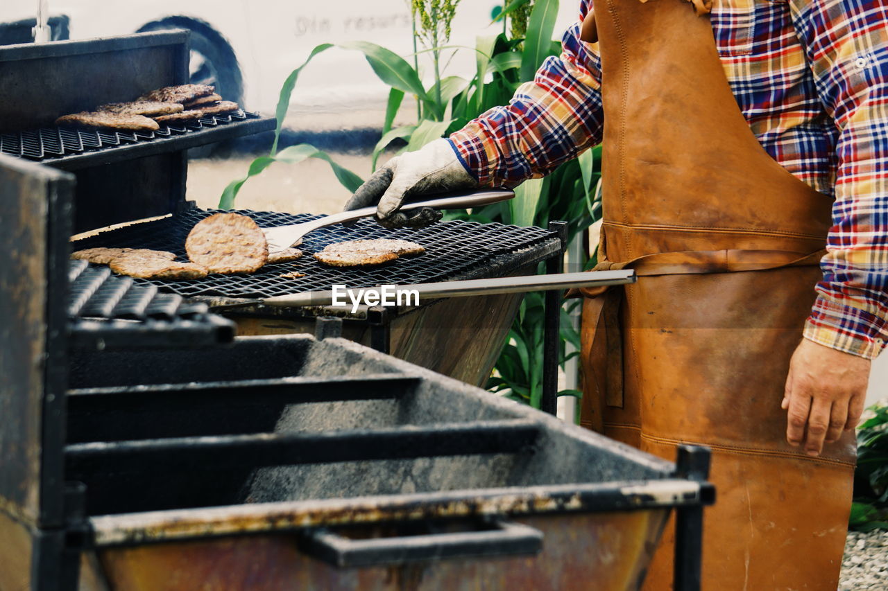 Midsection man preparing food on barbecue grill