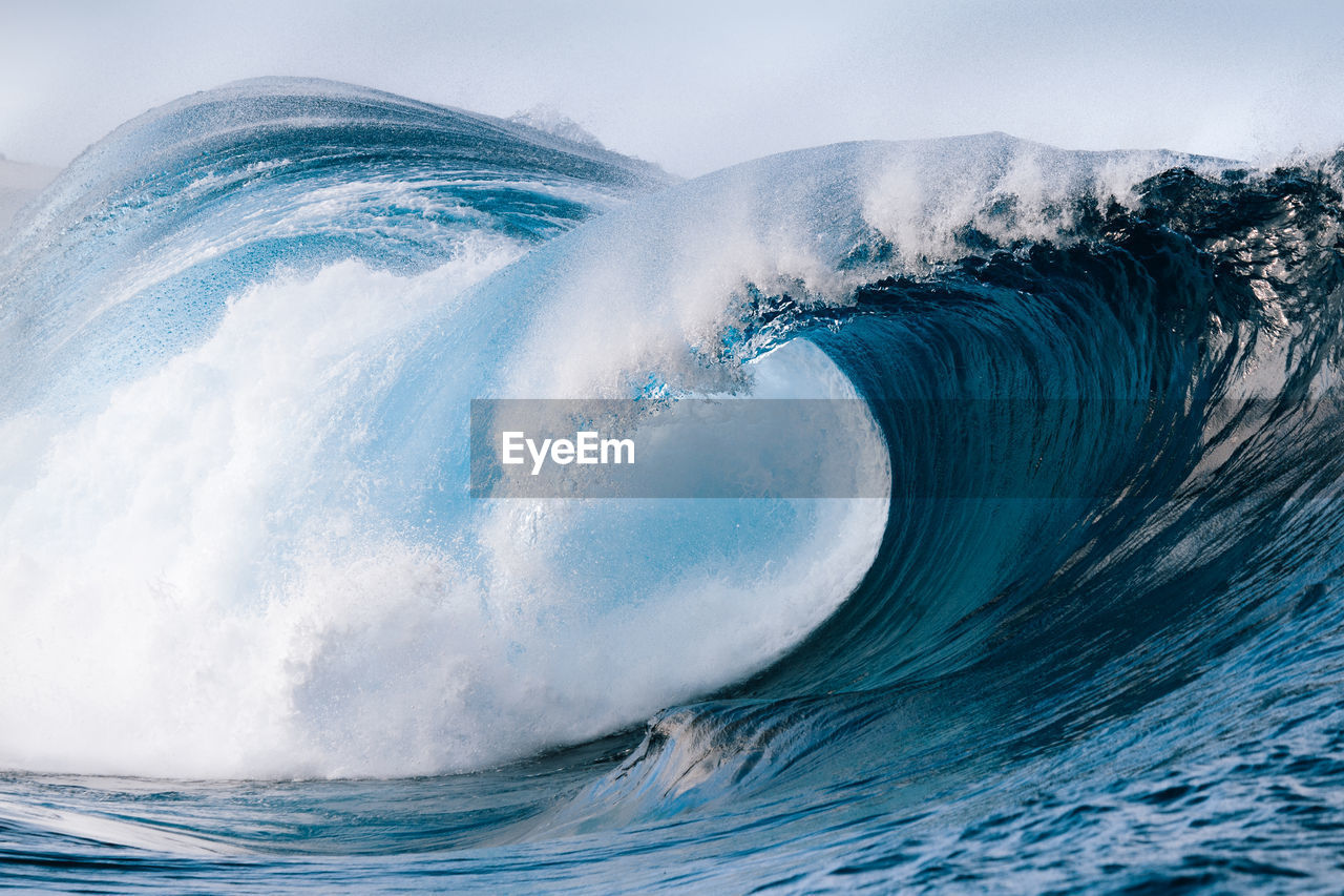 Powerful foamy sea waves rolling and splashing over water surface against cloudy blue sky