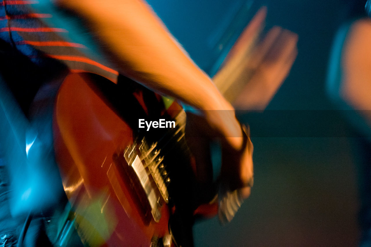 Midsection of man playing guitar at music concert