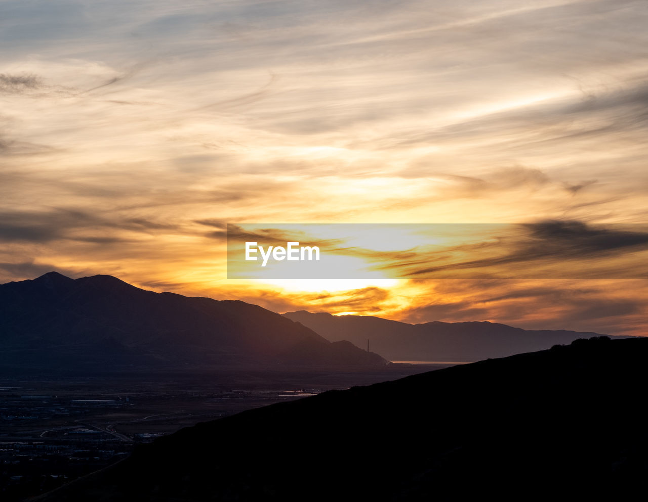 SCENIC VIEW OF SILHOUETTE MOUNTAINS AGAINST ORANGE SKY