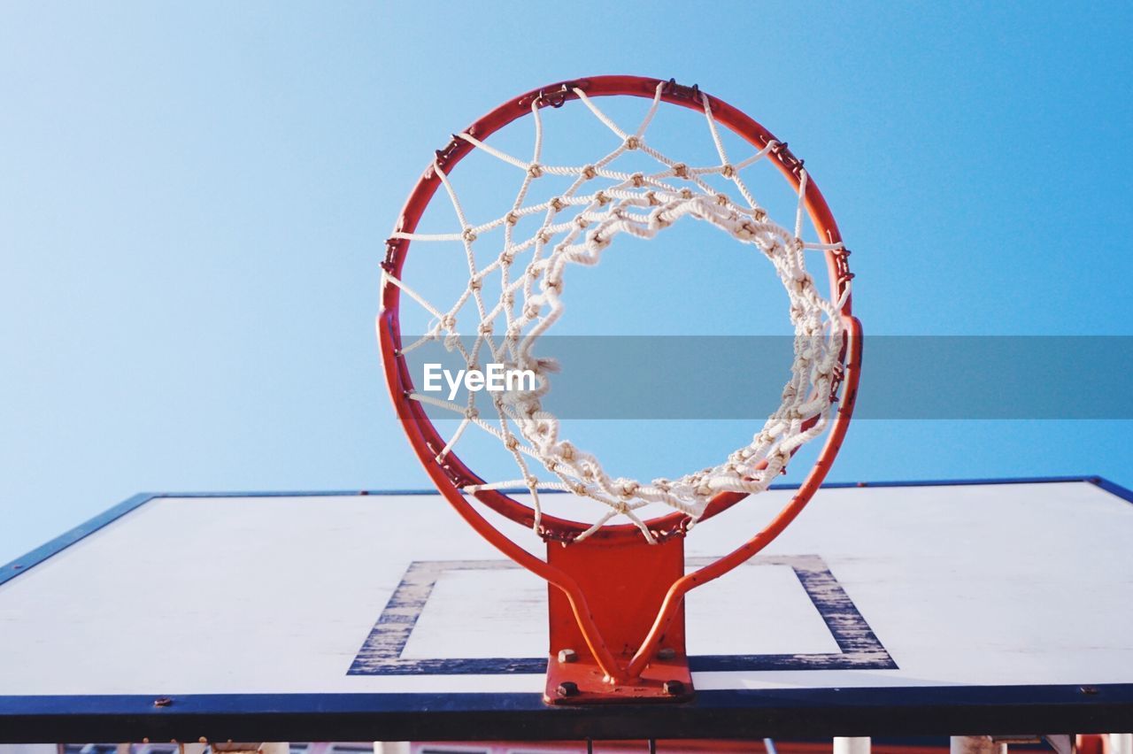 Directly below shot of basketball hoop against clear blue sky