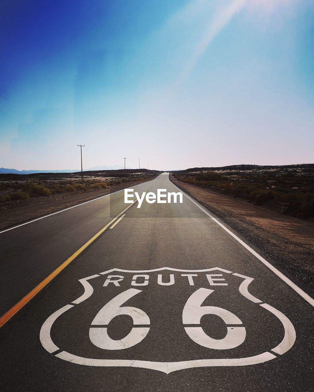 Route 66 written on road against blue sky
