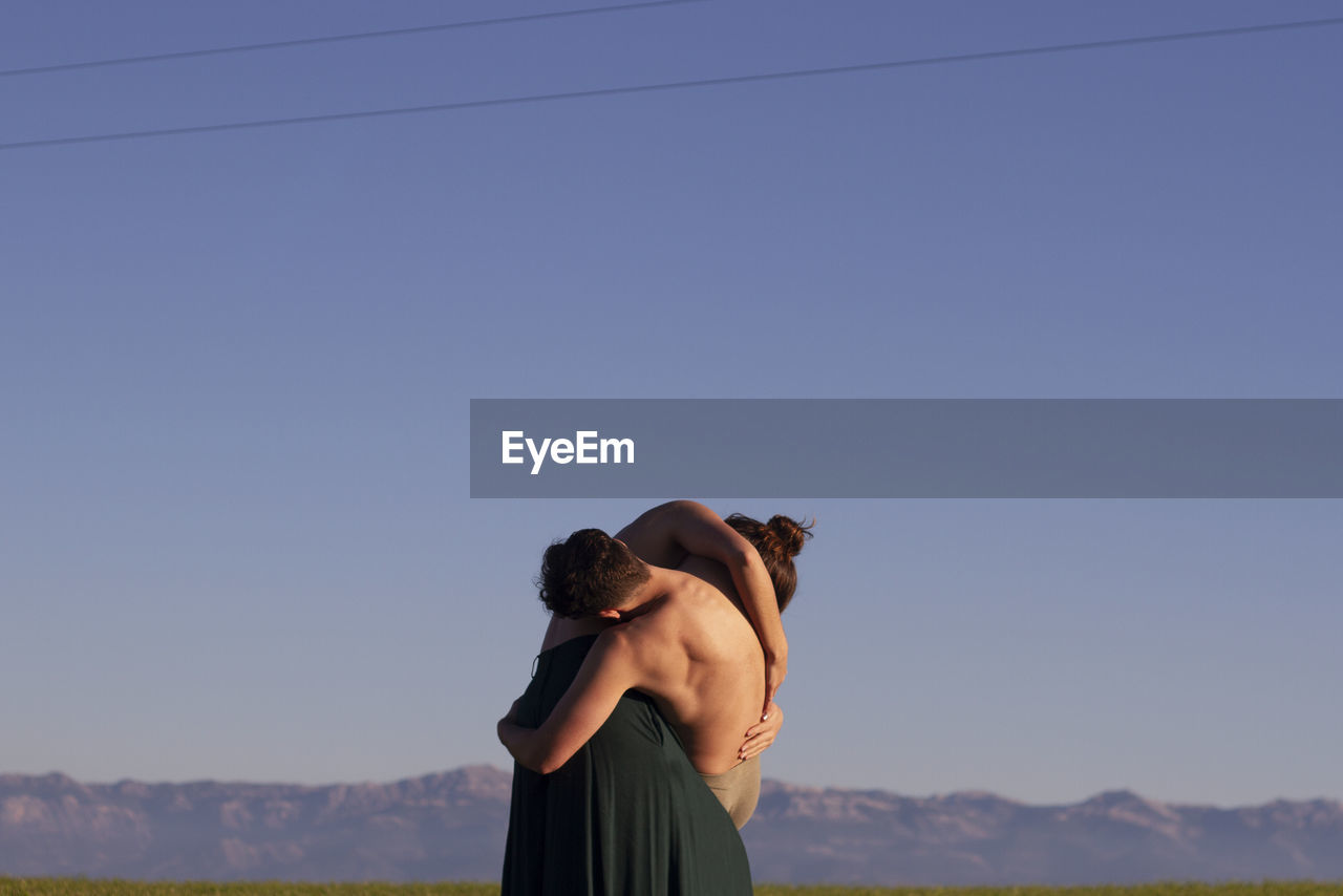 Couple embracing against mountains and clear sky