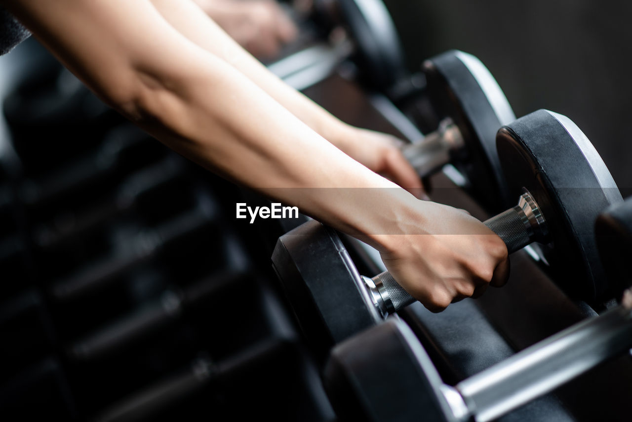 Cropped hands of woman holding dumbbells