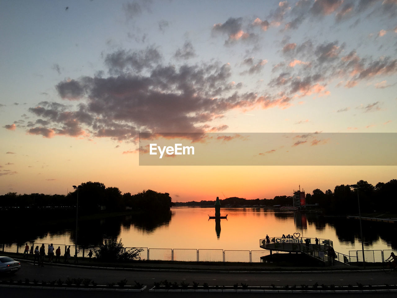 SILHOUETTE TREES BY LAKE AGAINST ORANGE SKY