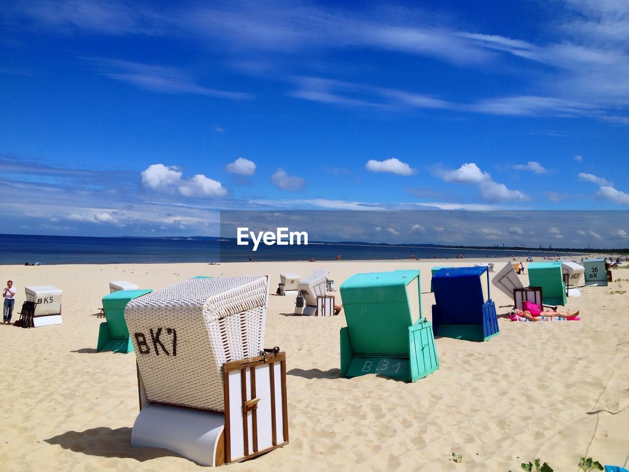 Hooded beach chairs on shore against sky