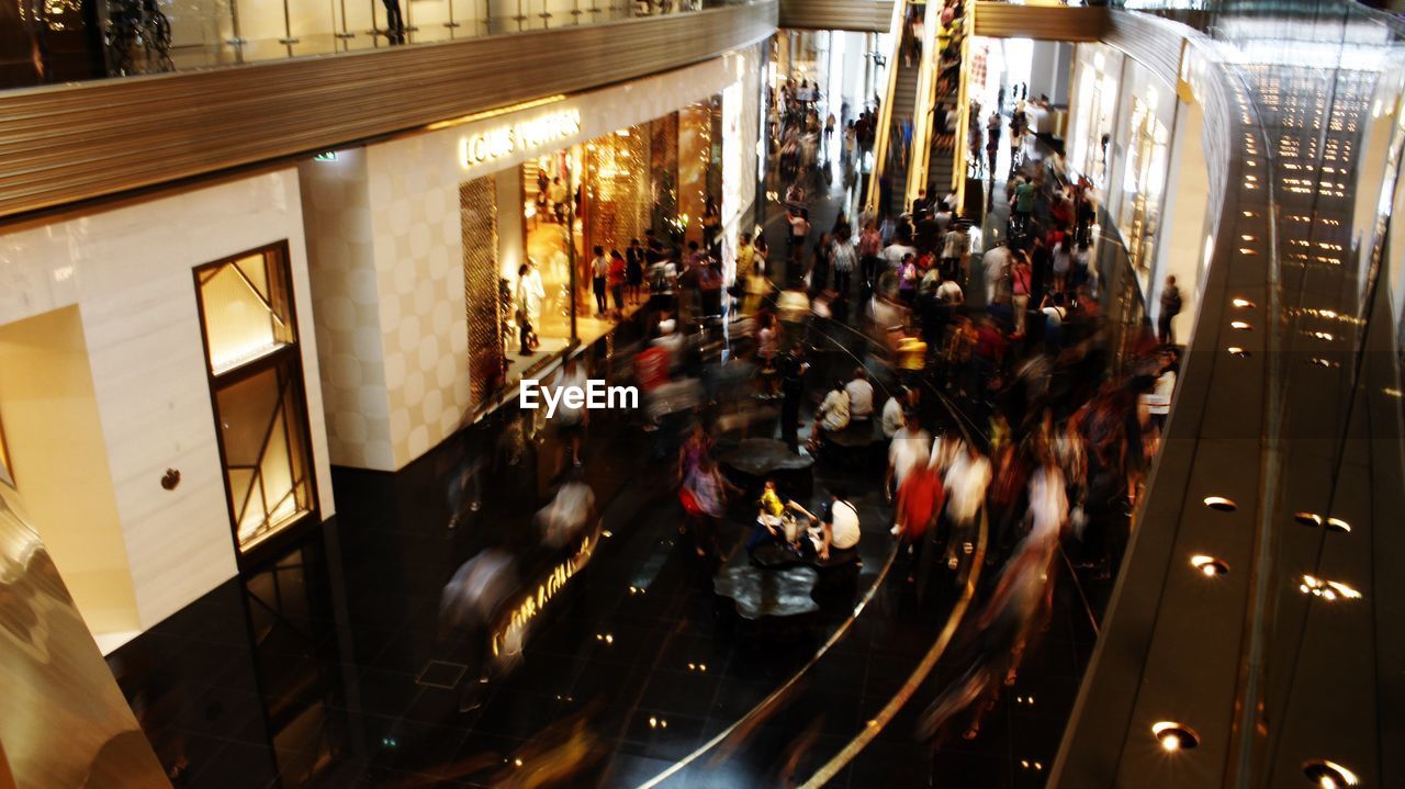 PEOPLE WALKING IN ILLUMINATED MODERN CITY AT NIGHT