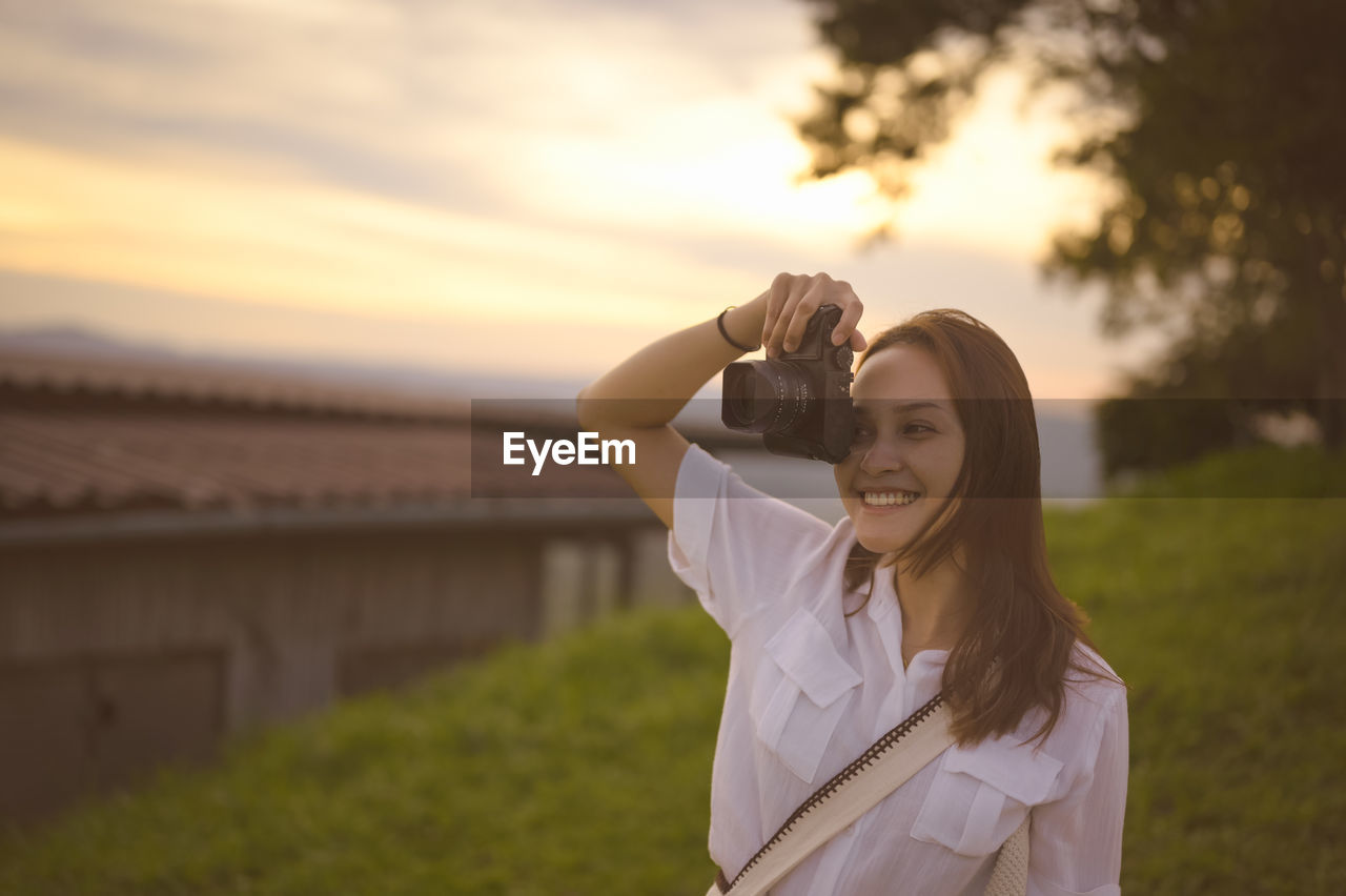 Young woman enjoying when her using camera ,golden hour in background