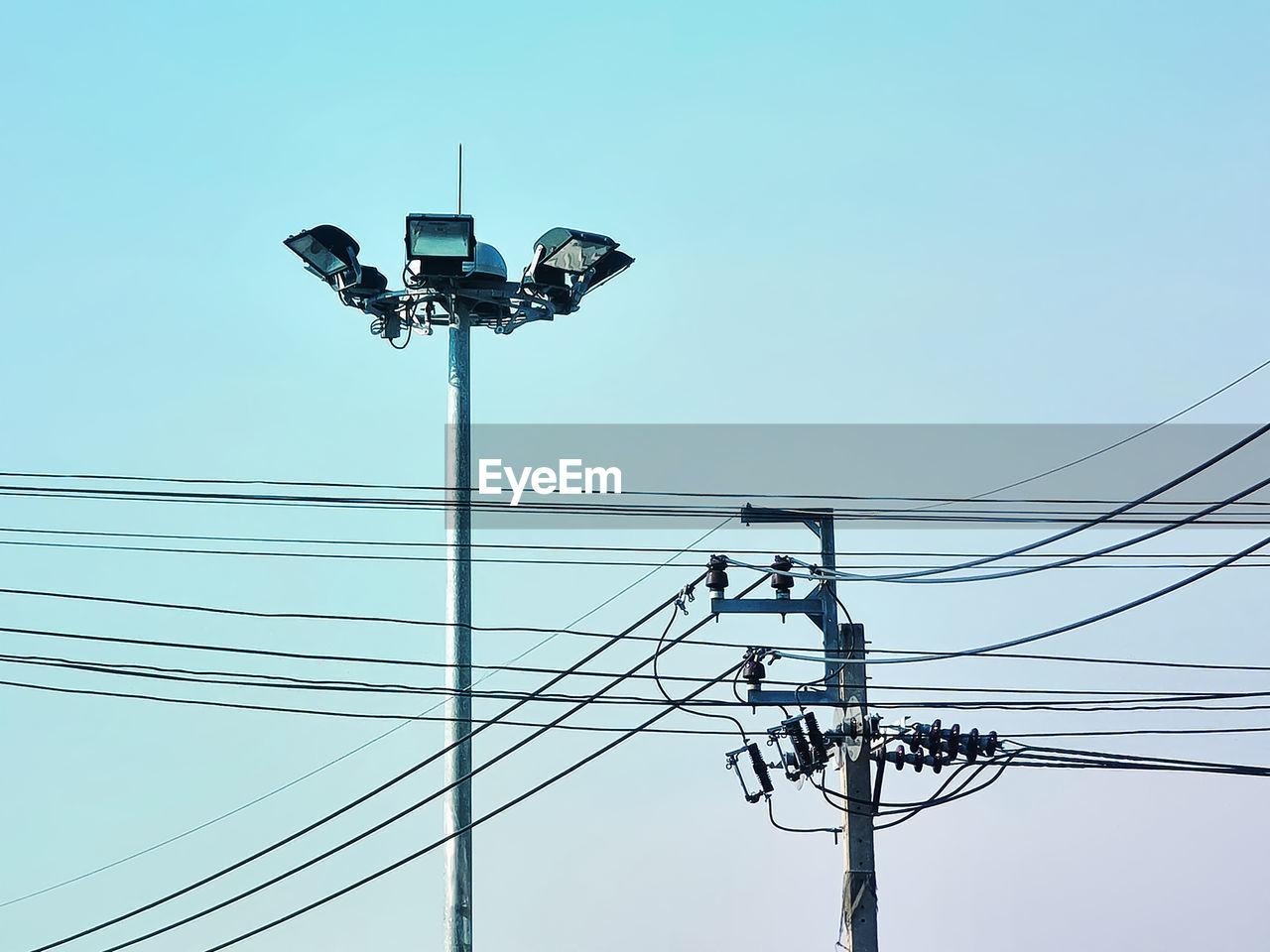 Electrical post and power lines against clear blue sky