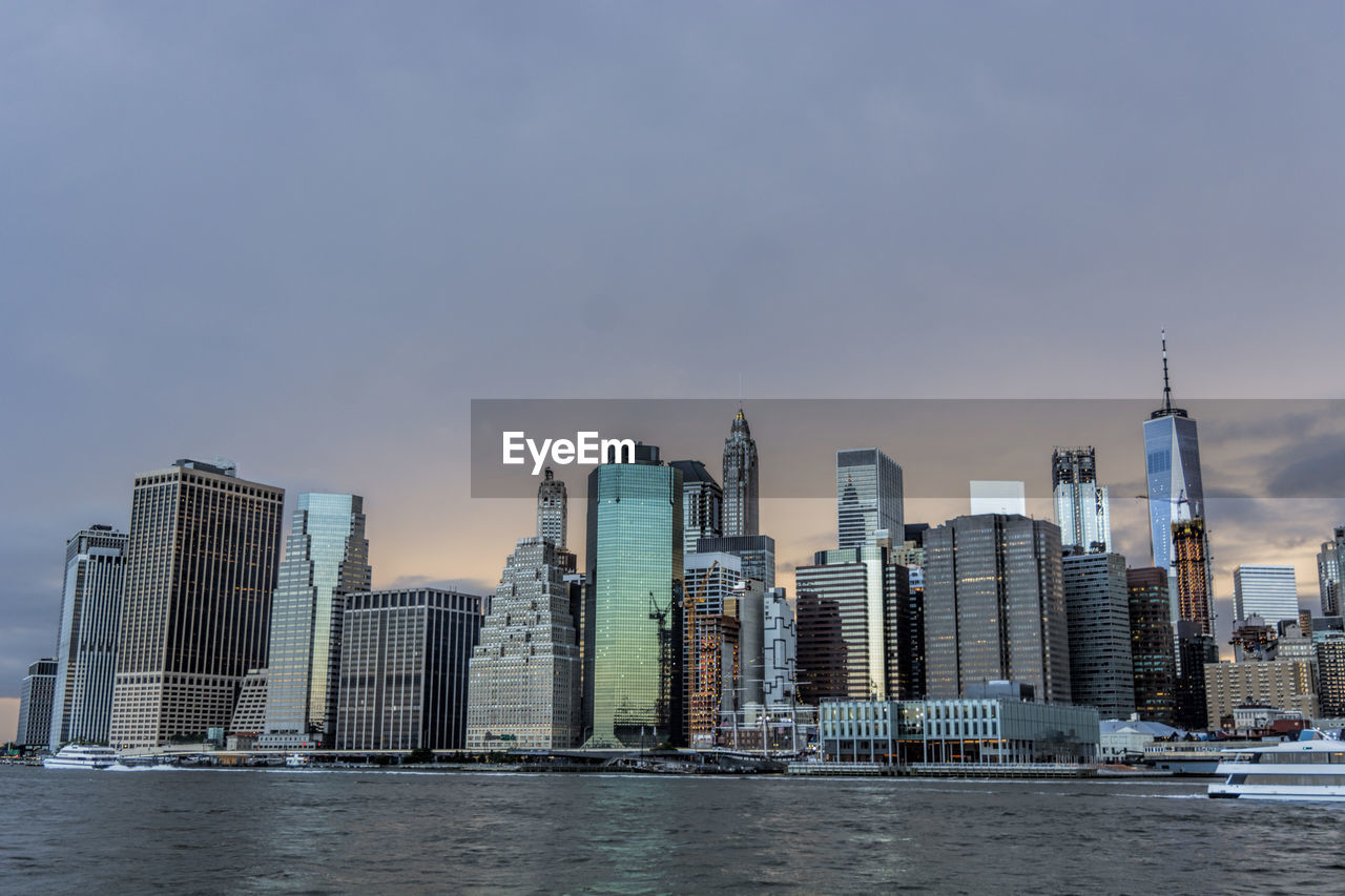 SEA BY MODERN BUILDINGS AGAINST SKY IN CITY