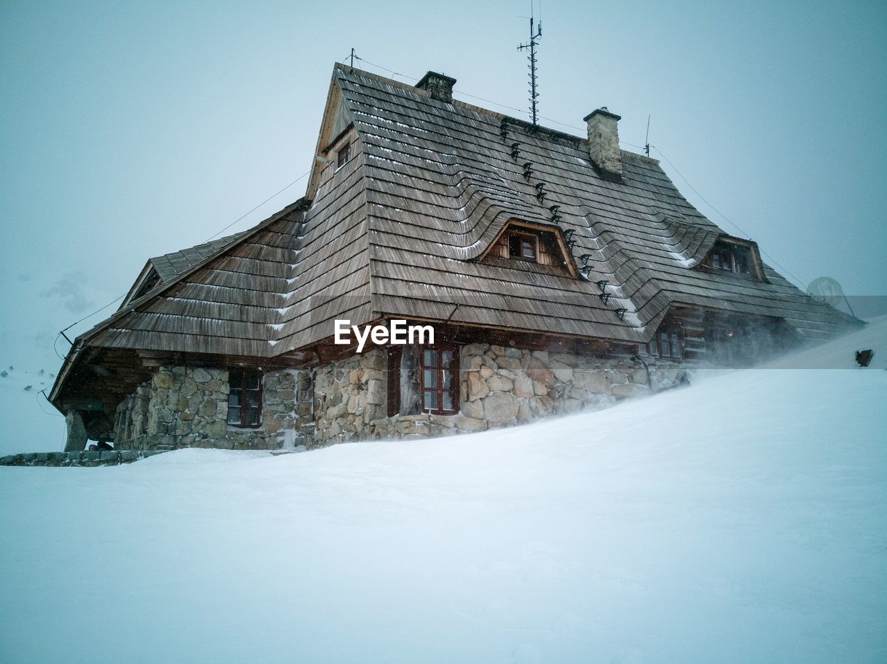 LOW ANGLE VIEW OF SNOW COVERED HOUSE AGAINST SKY