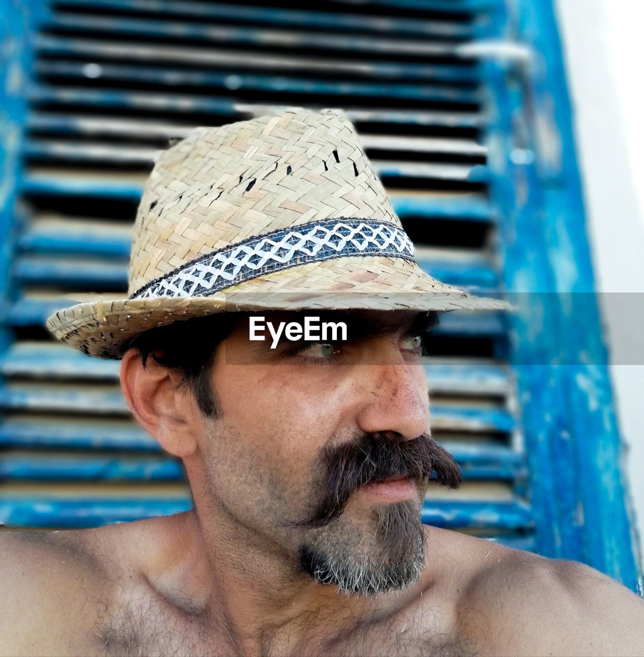 Close-up portrait of shirtless man wearing hat