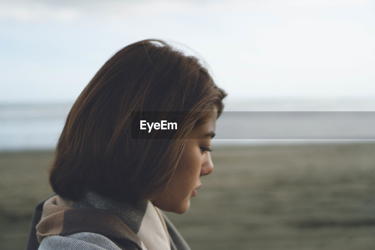 Side view of young woman with sea in background