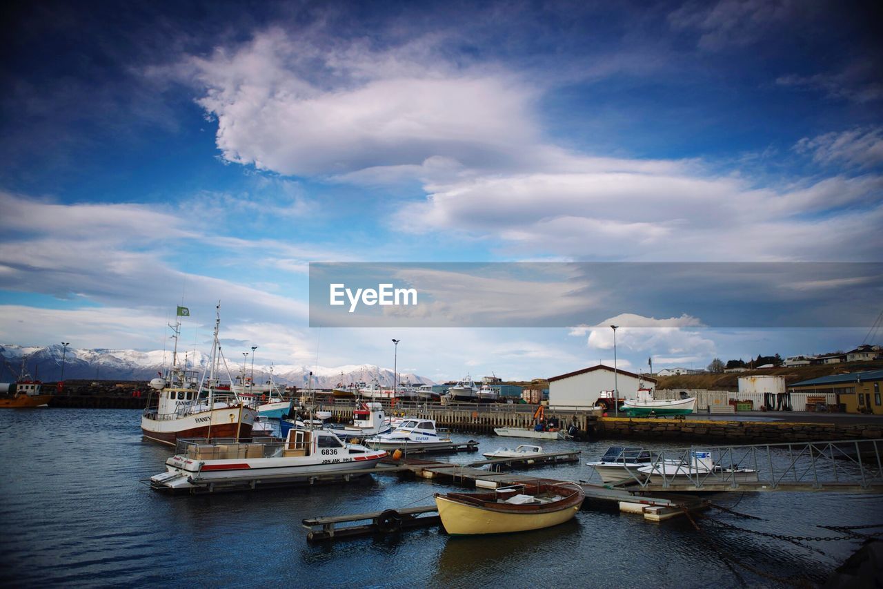 Boats moored at harbor against sky