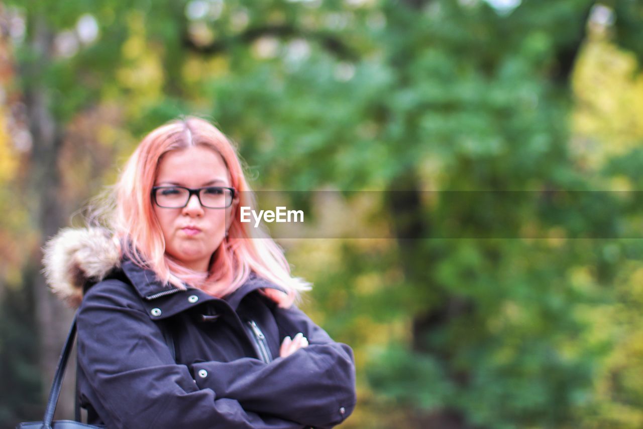 Portrait of woman standing against trees