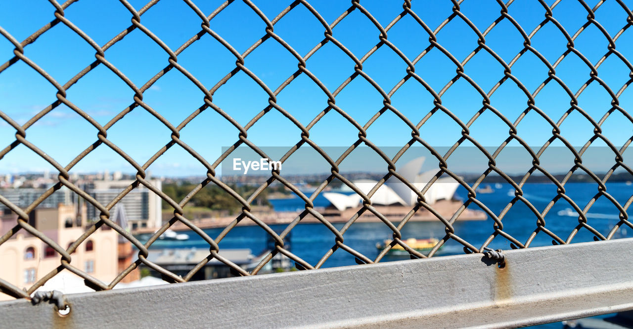 CHAINLINK FENCE AGAINST CLEAR BLUE SKY SEEN THROUGH METAL GRATE