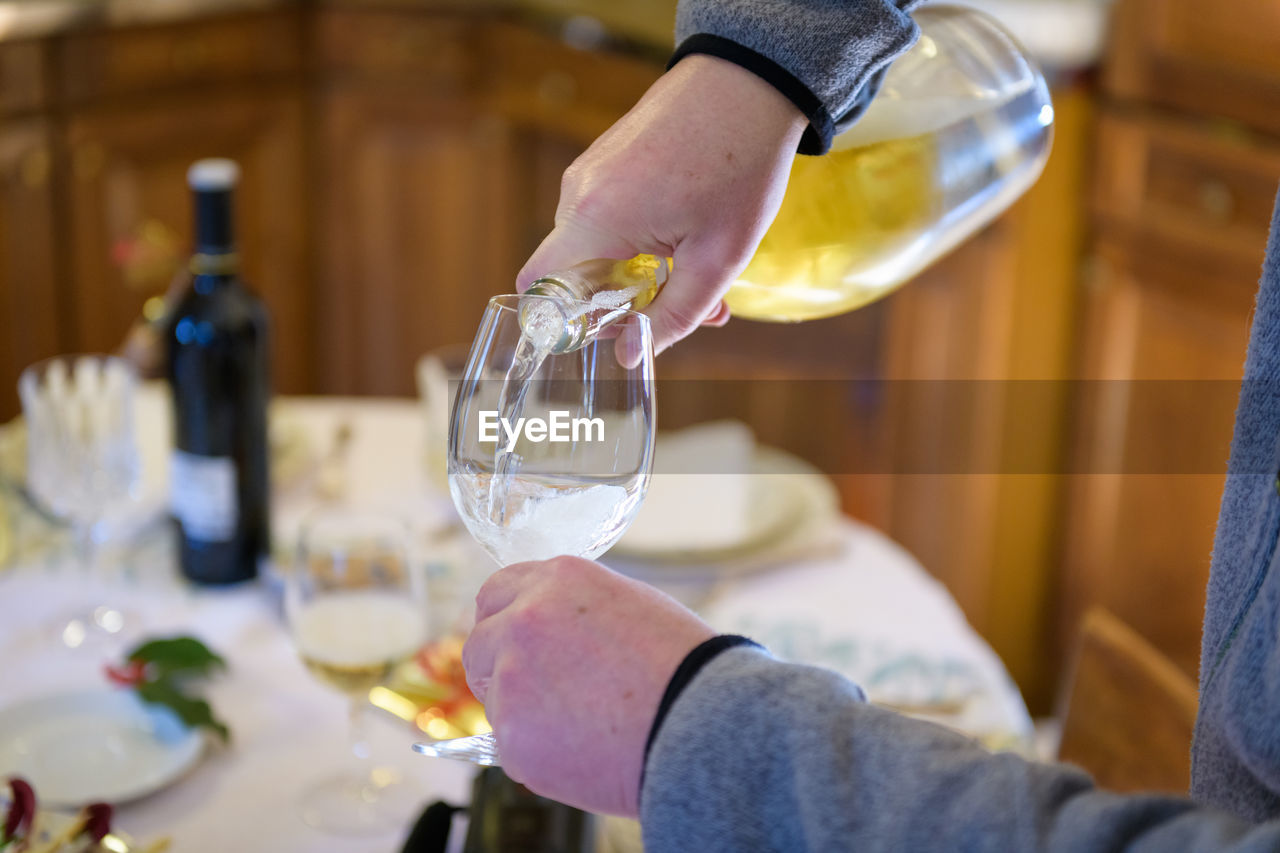 MIDSECTION OF MAN POURING DRINK IN GLASS