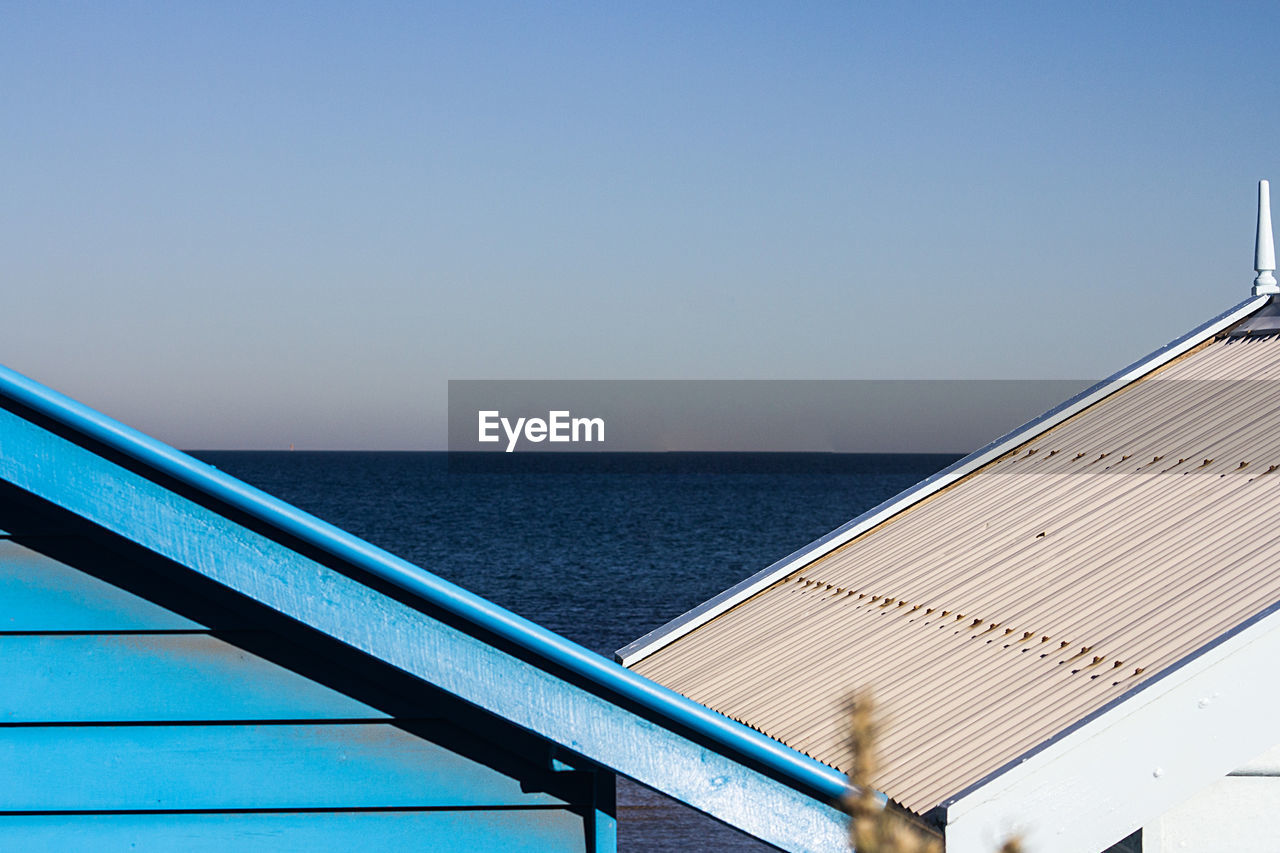 Scenic view of sea against clear blue sky and roof
