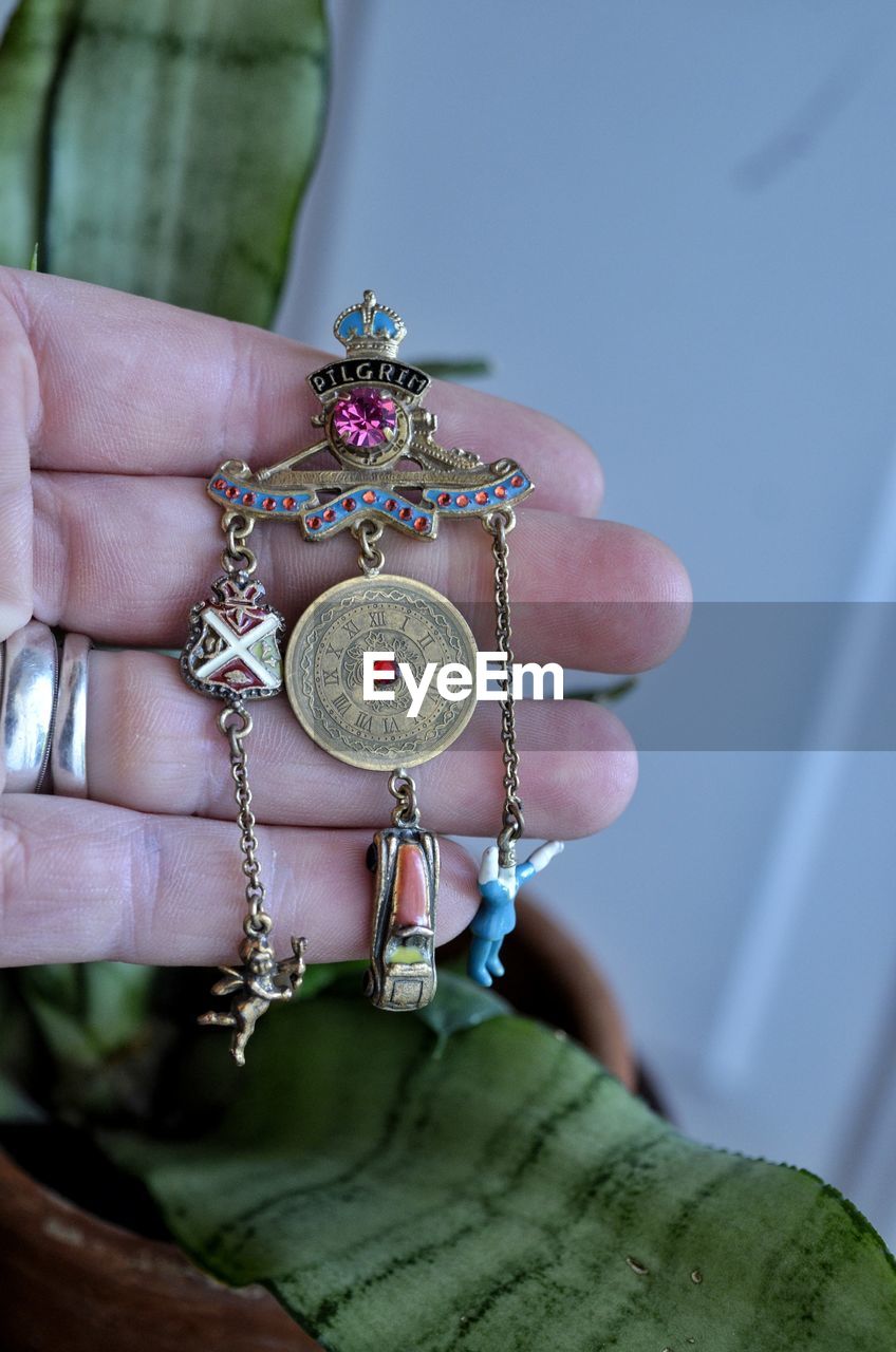 Cropped hand of person holding jewelry at home