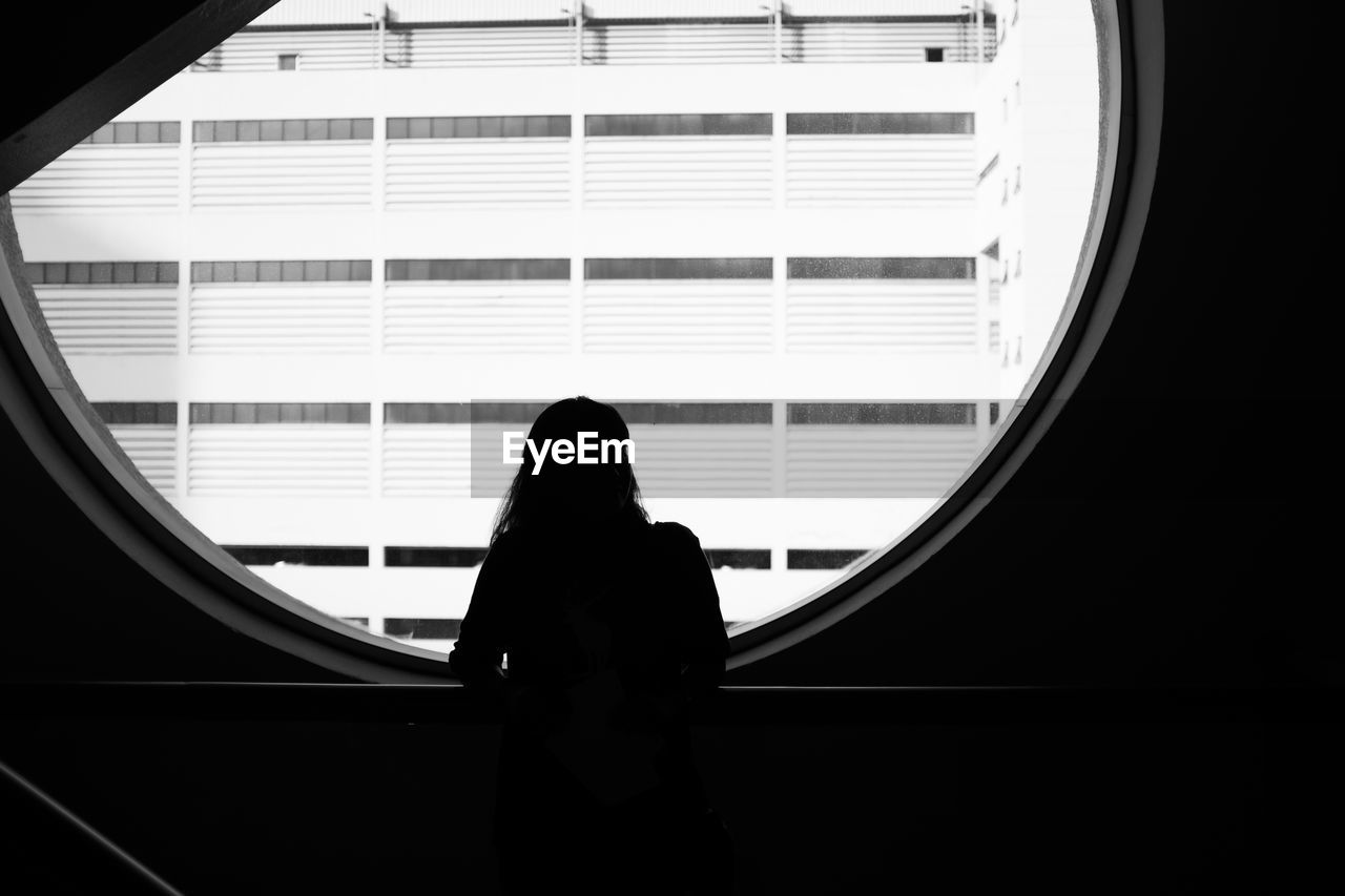 Rear view of woman looking through window