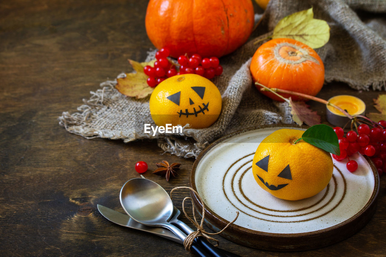 Halloween day decoration party. halloween wooden table setting with pumpkins and tangerines.