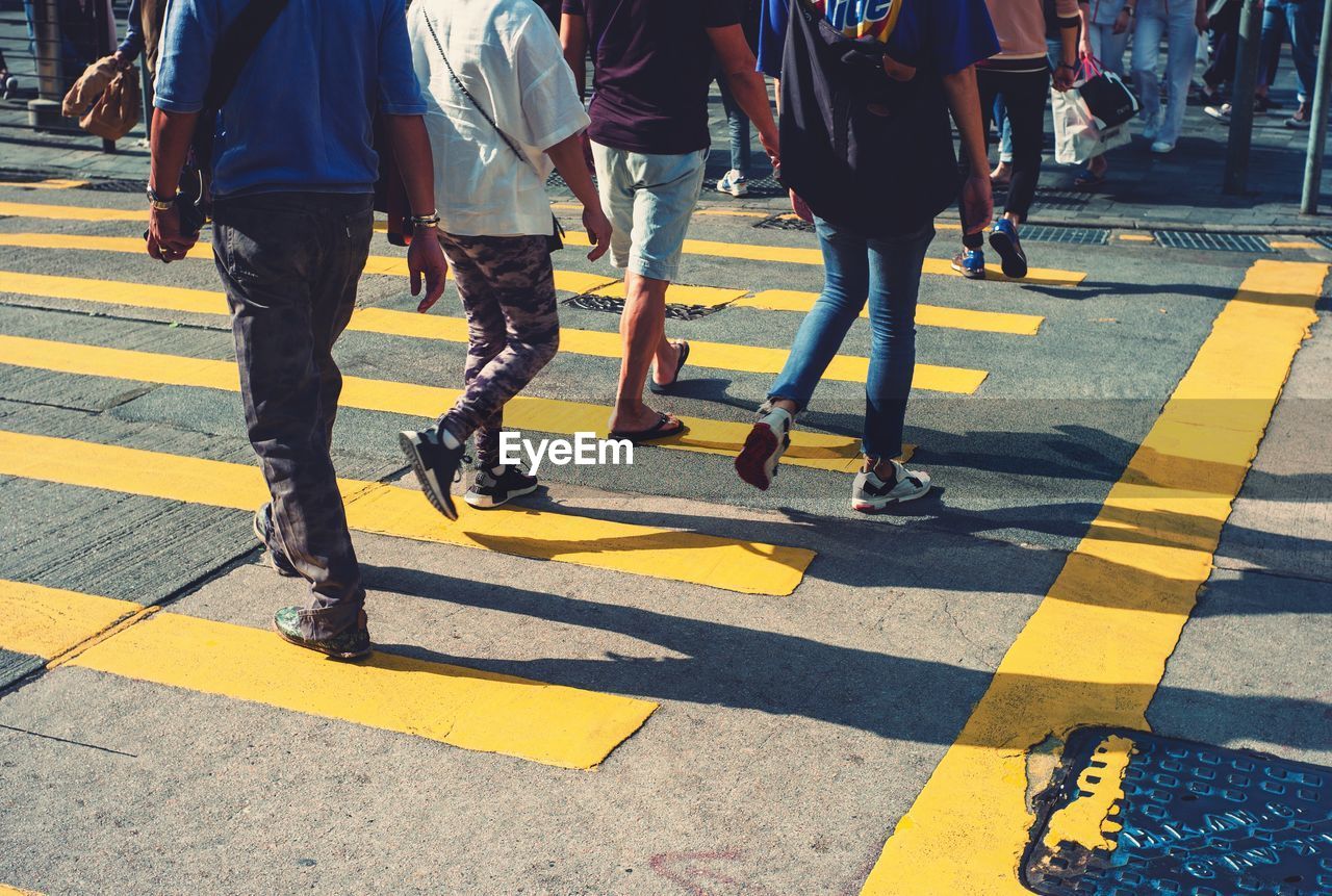 Low section of people walking on zebra crossing