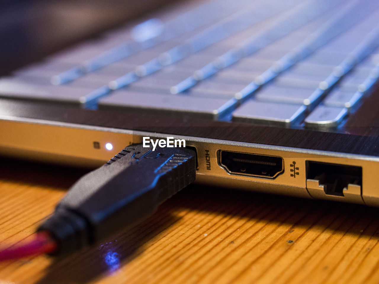 Close-up of usb cable attached to laptop on table