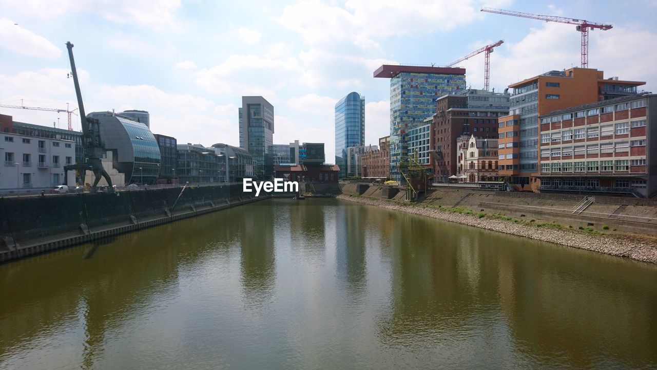 Reflection of buildings in river against sky in city