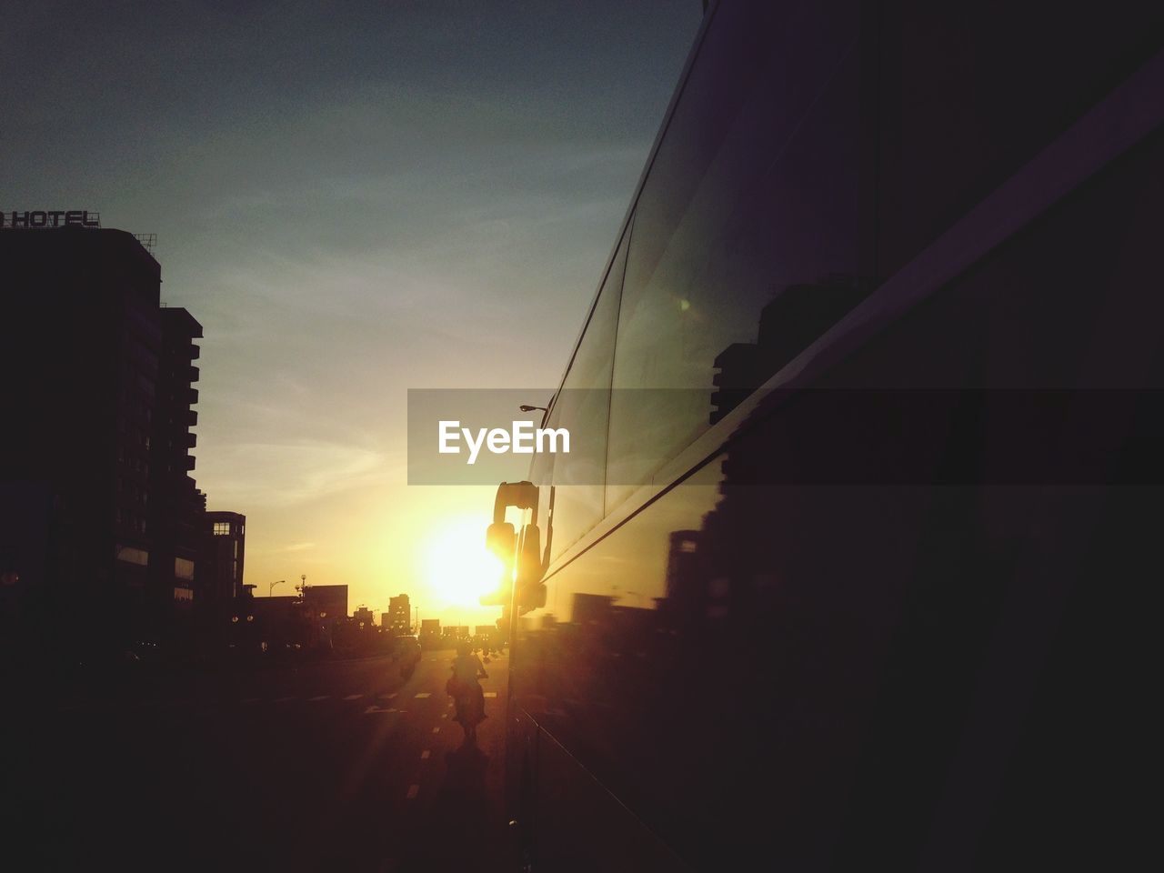 Vehicles on road along buildings at sunset