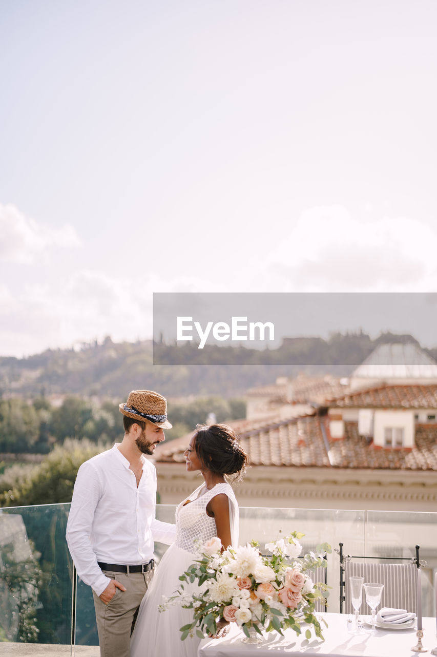 MAN AND WOMAN HOLDING FLOWER AGAINST SKY