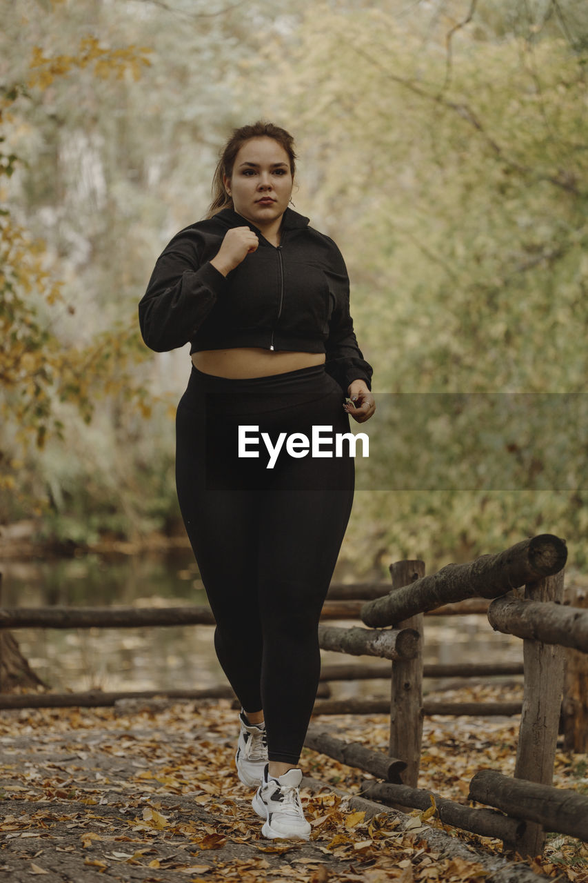 Determined overweight young woman jogging in autumn park