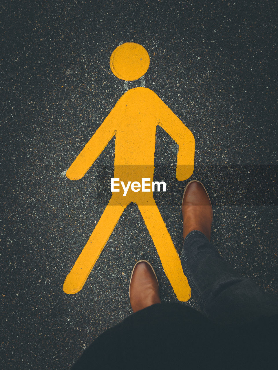 LOW SECTION OF MAN STANDING ON ROAD SIGN