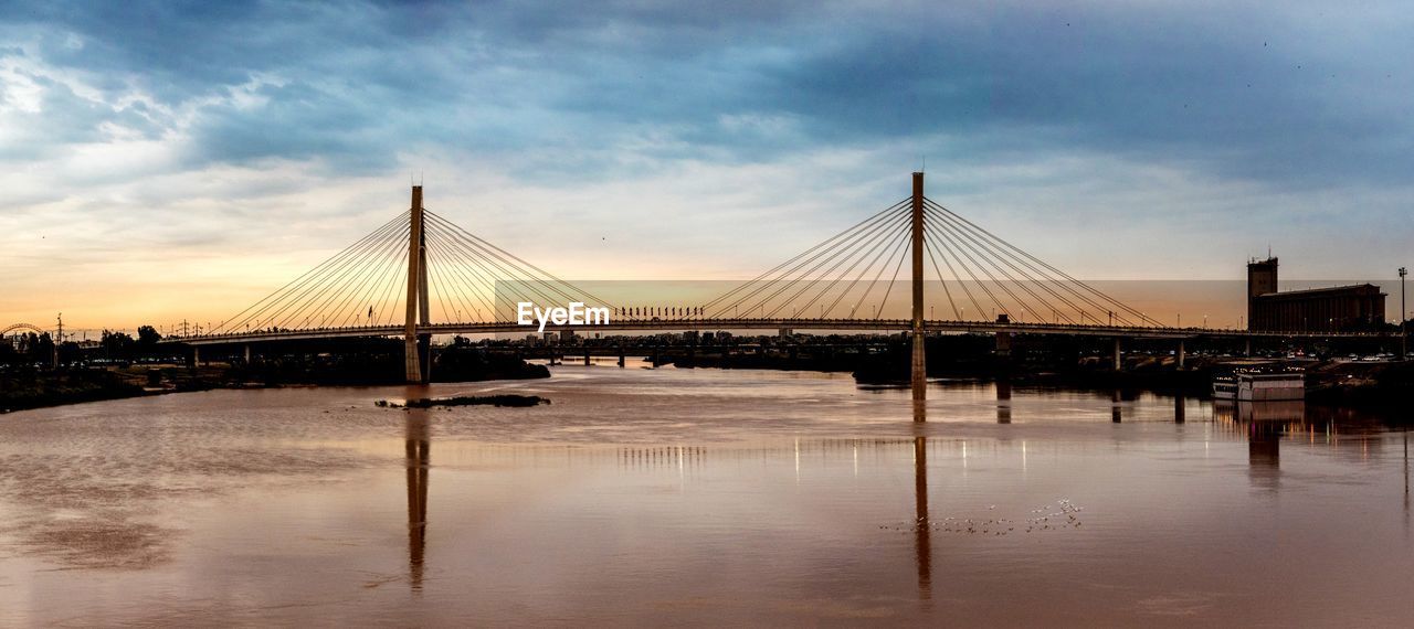 Suspension bridge over river against sky