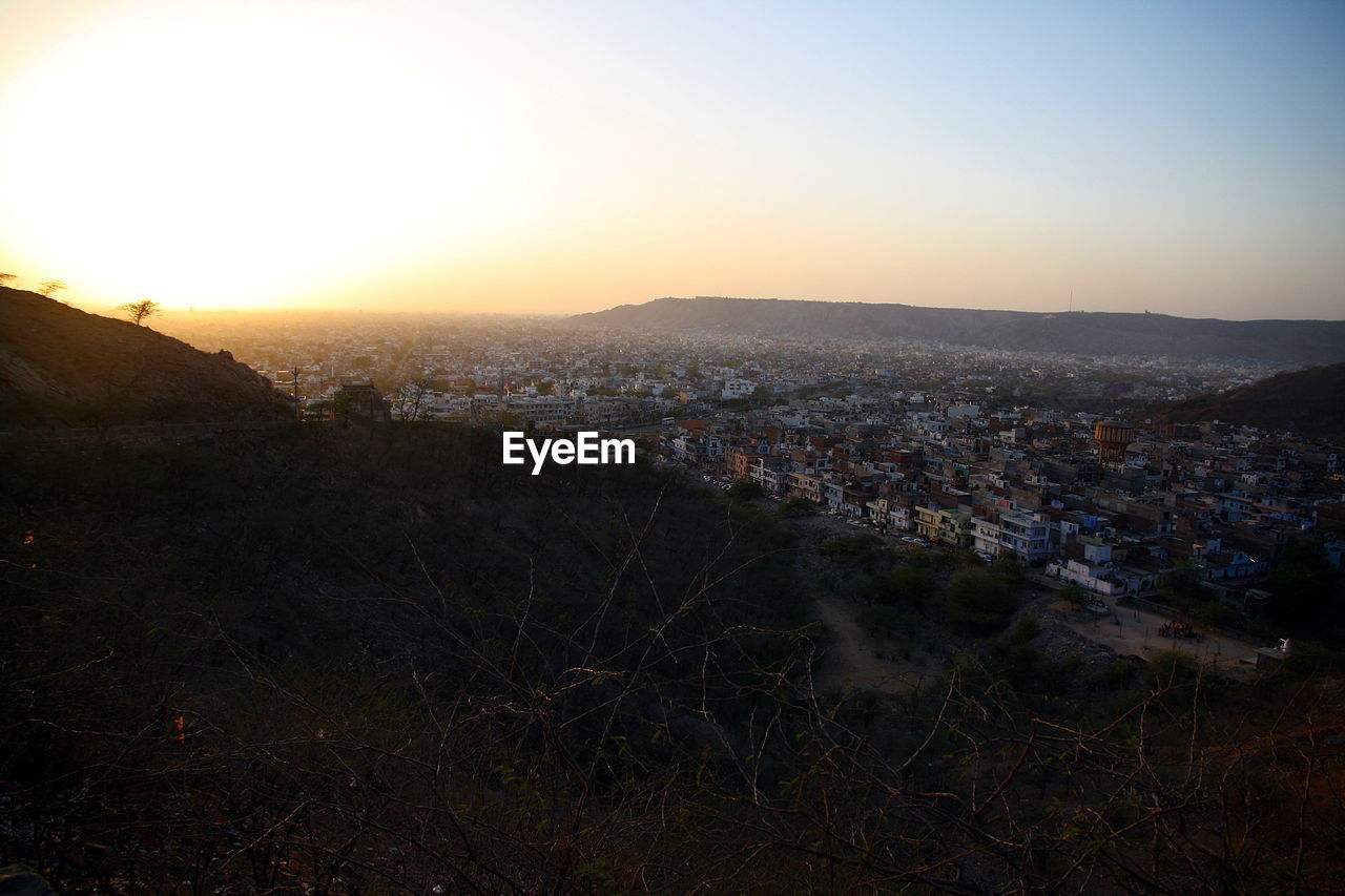 HIGH ANGLE VIEW OF TOWN AGAINST SKY DURING SUNSET