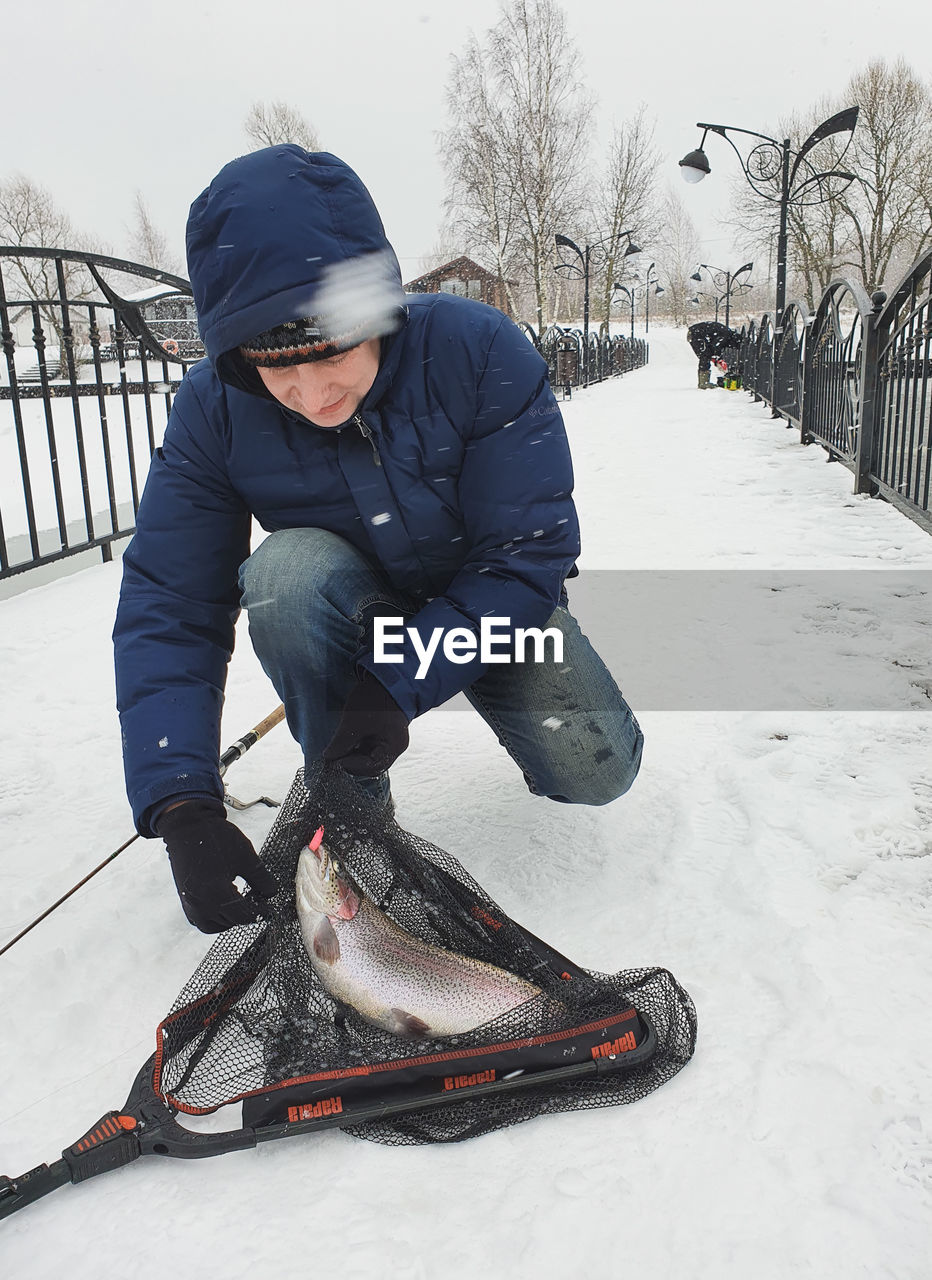 MAN WITH SNOW COVERED WITH UMBRELLA ON SNOWY DAY