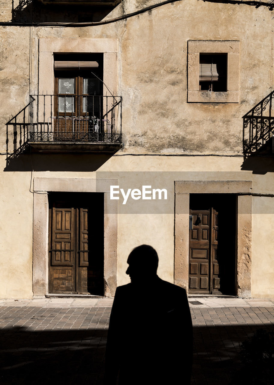 Silhouette of adult man in front of facade of an old building in sepulveda, spain