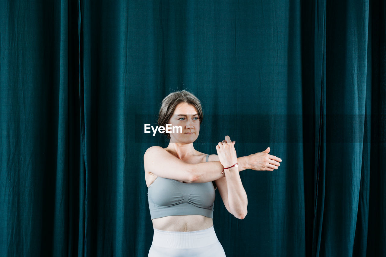 Woman exercising against curtain