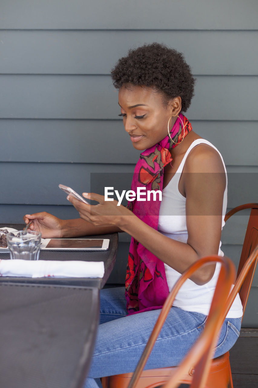 Young woman using her smart phone at a cafe