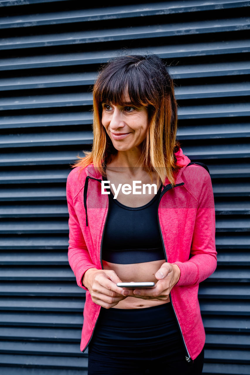 Portrait of female athlete posing with mobile phone