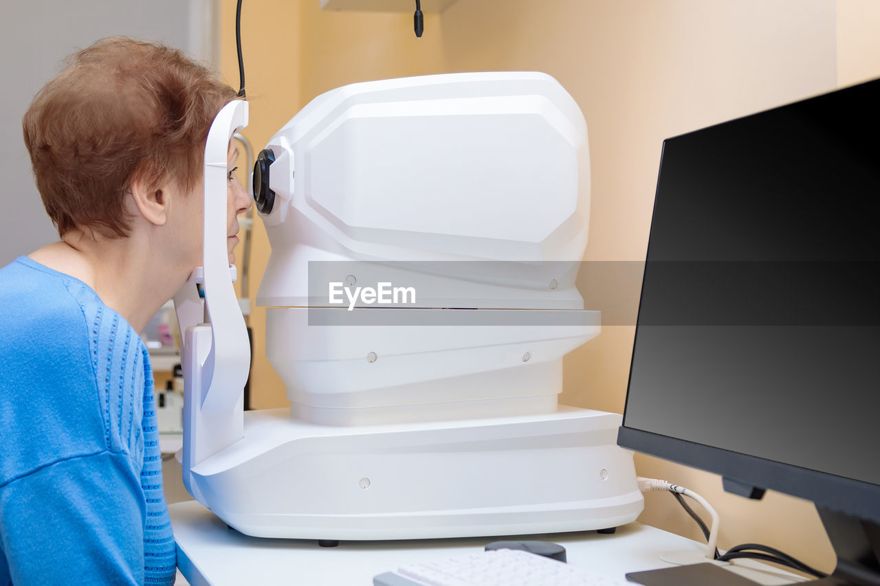 An adult woman at an ophthalmologist's appointment checks her vision on a special apparatus. 