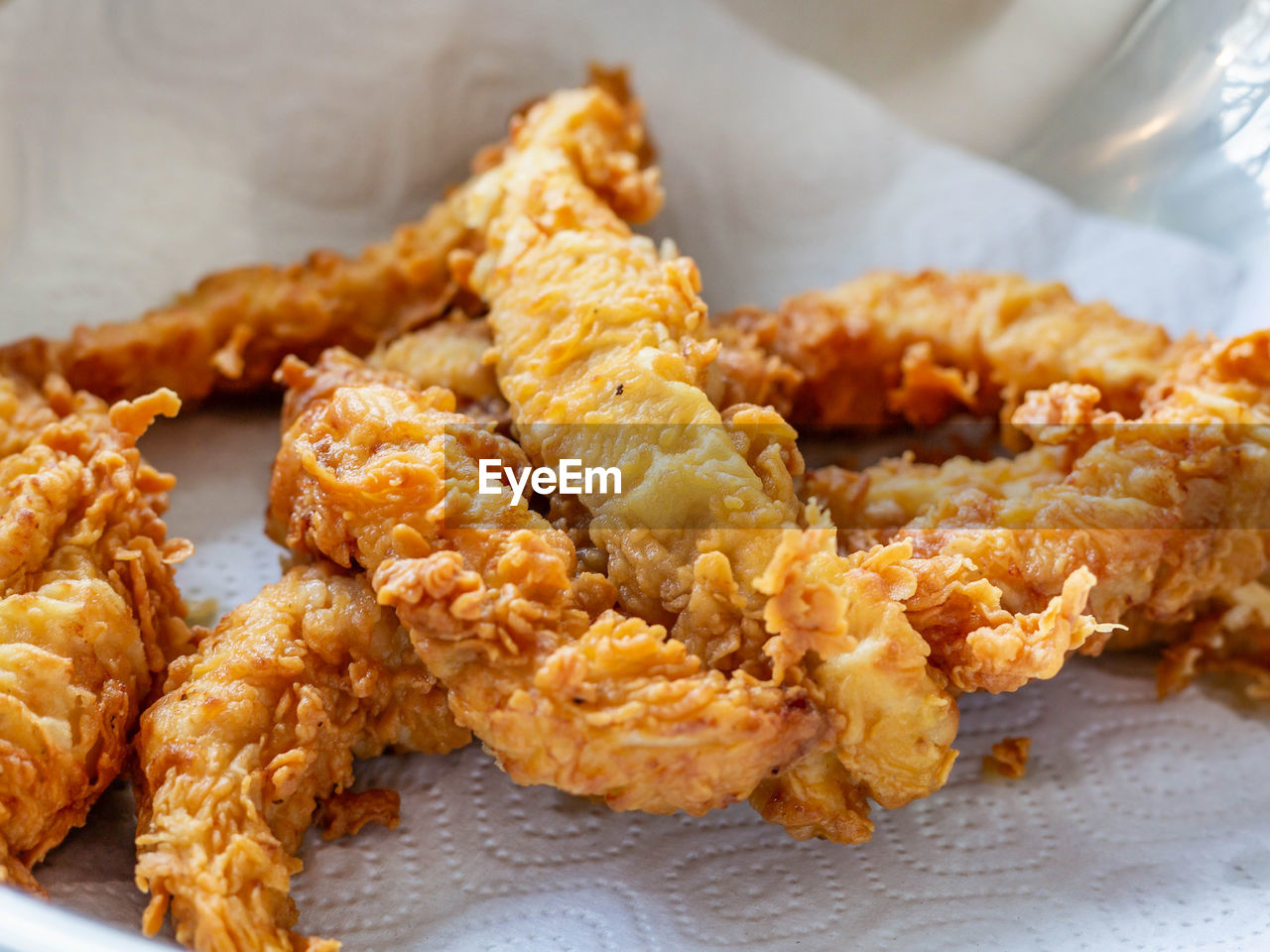 Large oblong pieces of breaded chicken are laid out on a napkin after frying to drain excess oil