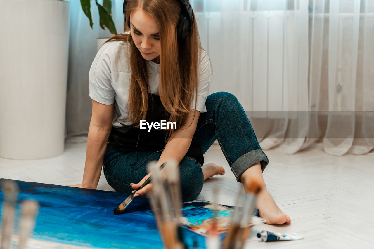 Woman painting on canvas while sitting at home